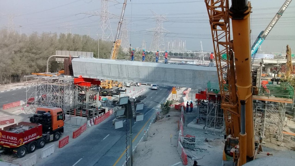 Infrastructure crews installing precast bridge beam over active route