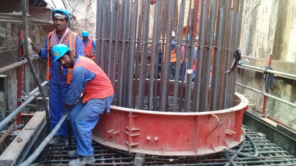 Certified operatives erecting pile cap rebar cage with full PPE