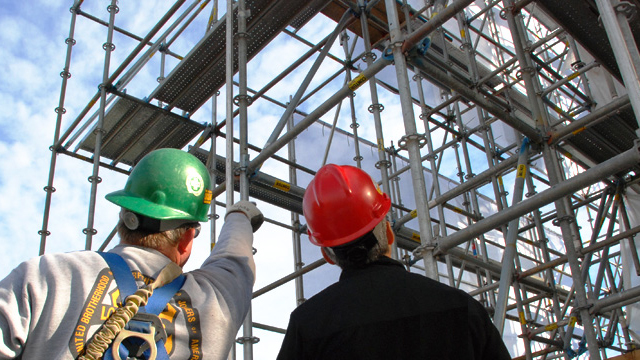 Supervisors inspecting modular scaffolding installation on a high-rise project
